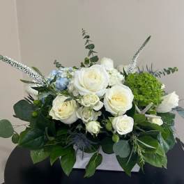 White roses and green hydrangea arranged in a low white container