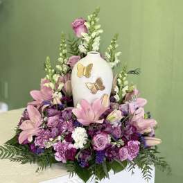 Pink and purple floral arrangement around a white butterfly vase