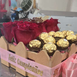 Red roses and gold-wrapped chocolates in a pink ribboned box