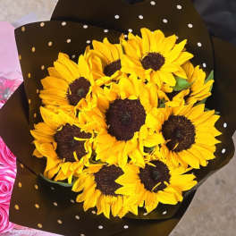Bouquet of yellow sunflowers wrapped in black polka-dot paper