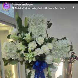 White floral standing spray on an easel with a blue ribbon