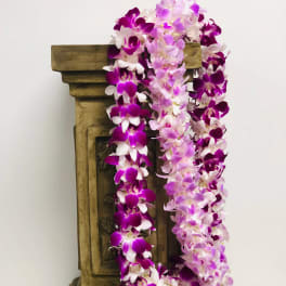 Purple and pink orchid garlands draped over a wooden pedestal