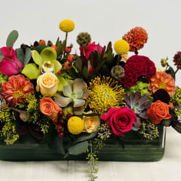 Colorful mixed flower arrangement in a rectangular green vase