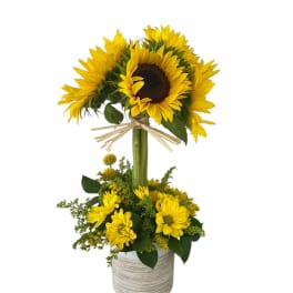 Sunflower arrangement in a gray textured pot with a raffia bow