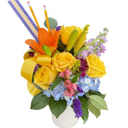 Yellow roses and mixed flowers in a white vase with pencils and rulers