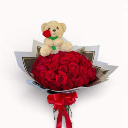 Bouquet of red roses with a teddy bear topper and red ribbon