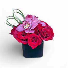 Pink roses and orchids in a black square vase