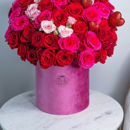 Large bouquet of red and pink roses in a pink hat box with heart picks