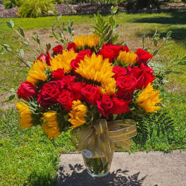 Bouquet of red roses and yellow sunflowers in a glass vase