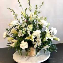 White lilies and carnations in a wicker basket arrangement