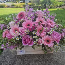 Pink gerbera daisies and roses in a wooden box with small daisies