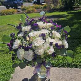 Bouquet of white roses and purple flowers in a glass vase