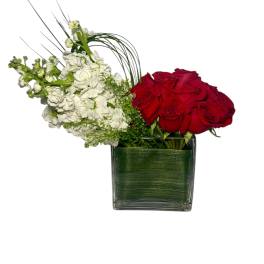Red roses and white flowers in a square glass vase