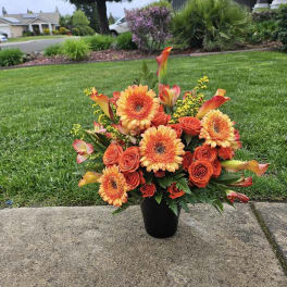 Orange and yellow floral arrangement in a black vase