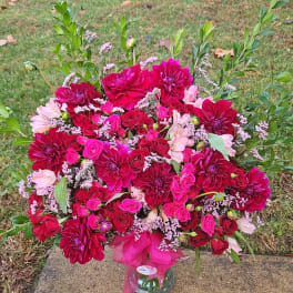 Large pink and red floral arrangement in a glass vase