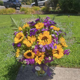 Bouquet of sunflowers and purple flowers in a glass vase