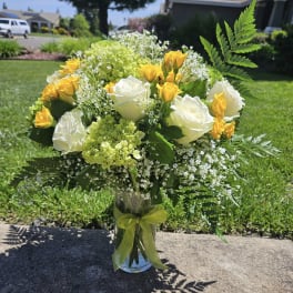 Bouquet of white and yellow roses in a glass vase with a ribbon