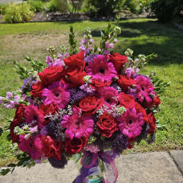 Bouquet of red roses and pink gerbera daisies in a glass vase