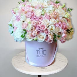 Large pastel bouquet of pink and white roses in a lavender hat box