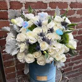 White rose bouquet in a blue hatbox with baby-themed picks