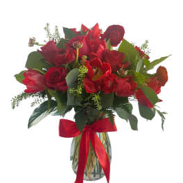Red floral bouquet in a glass vase with a red ribbon