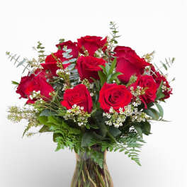 Red roses arranged in a glass vase with small white filler flowers