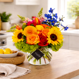Bright mixed bouquet in a clear glass vase with sunflowers and roses