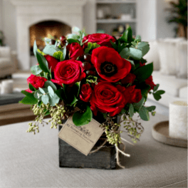 Red roses and a red anemone in a black square vase