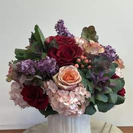 Bouquet of red and peach roses with pink hydrangeas in a white vase