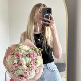 Woman holding a pink and white mixed flower bouquet in front of a mirror