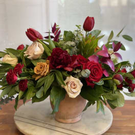 Mixed red and cream roses in a low terracotta vase