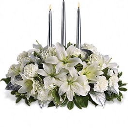 White floral centerpiece with three lit silver candles