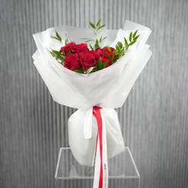 Bouquet of red roses wrapped in white paper with a red ribbon