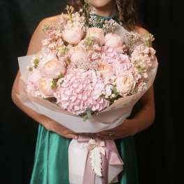 Large pink bouquet of roses and hydrangeas wrapped in pale paper