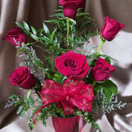 Bouquet of red roses in a ribbed vase with a red bow