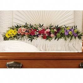 Colorful floral spray arranged across a wooden casket