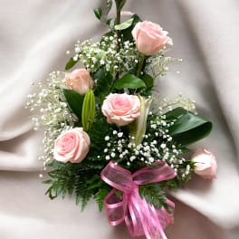 Pink roses arranged with baby's breath and a pink ribbon