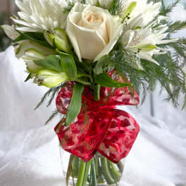White rose and lily bouquet in a glass vase with a red ribbon