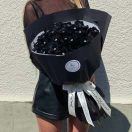 Large bouquet of black roses wrapped in black paper with a white ribbon