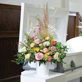 Floral casket spray with pink, yellow, and white flowers