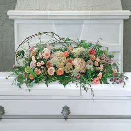 Pastel floral arrangement on a white casket