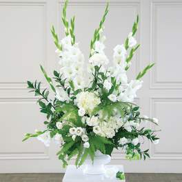 White floral arrangement in a white vase with tall green spikes