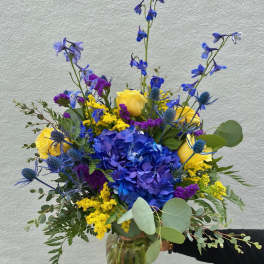 Blue and yellow mixed bouquet in a glass vase