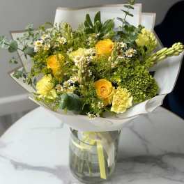 Yellow roses and small white daisies in a glass vase
