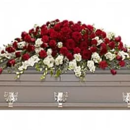 Red and white floral casket spray on a gray casket