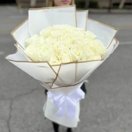 Bouquet of white roses wrapped in white paper with a ribbon
