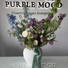 Mixed bouquet of blue and purple flowers in a white vase