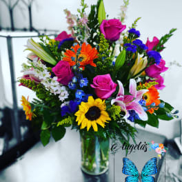 Mixed bouquet of roses, lilies, and sunflowers in a glass vase