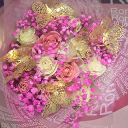 Bouquet of pink and cream roses with bright pink filler and gold butterfly decorations