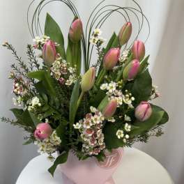 Pink tulips and white filler flowers in a pink heart-shaped vase